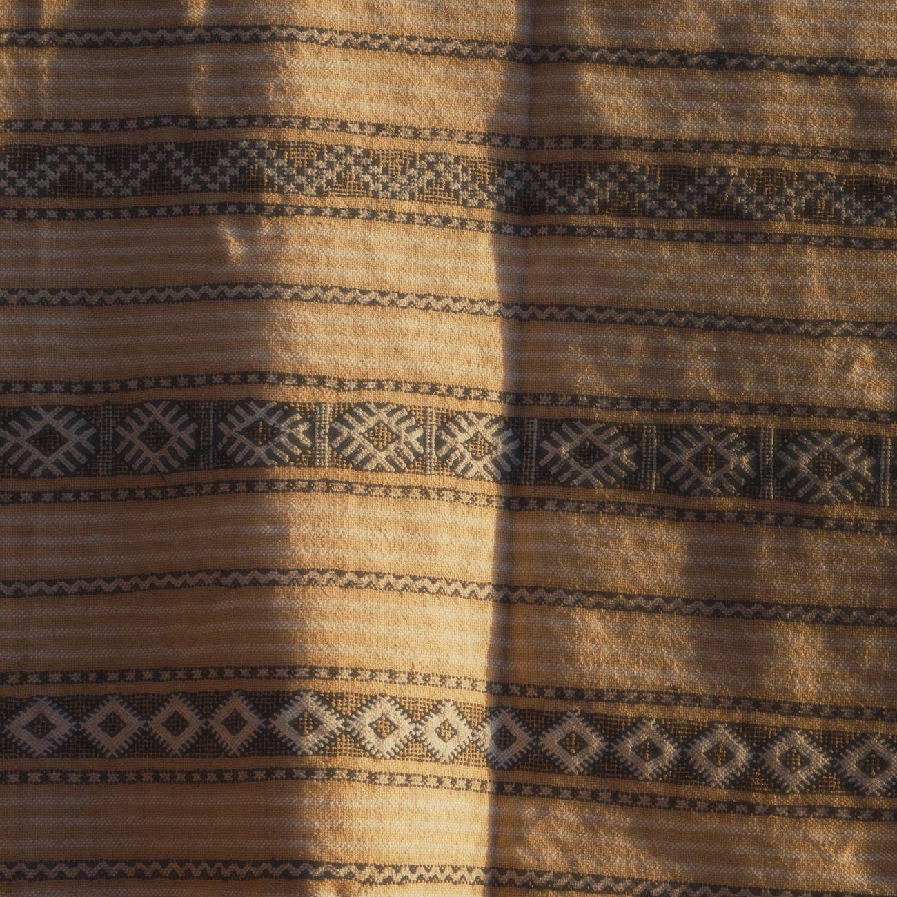 Artisan threading multicolored silk yarns through a traditional jacquard loom in a Kyoto Nishijin weaving workshop.