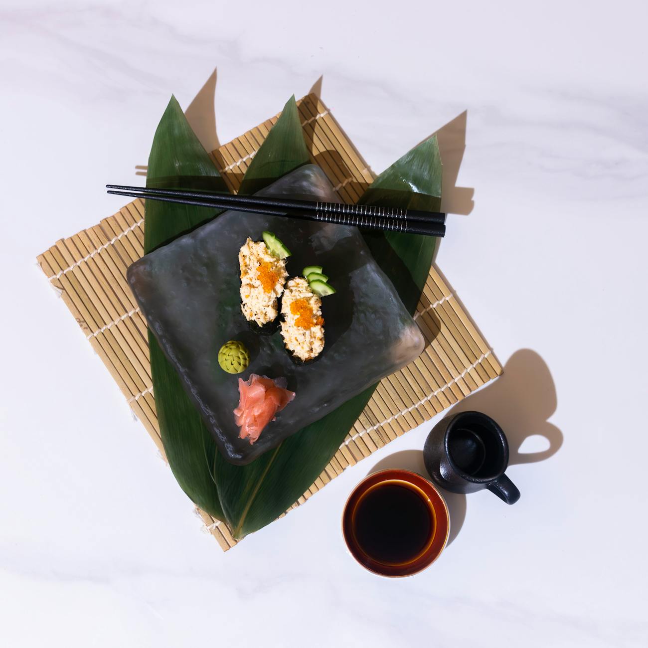Hands holding chopsticks over a traditional Japanese meal with rice bowl, miso soup, and small side dishes on lacquerware.