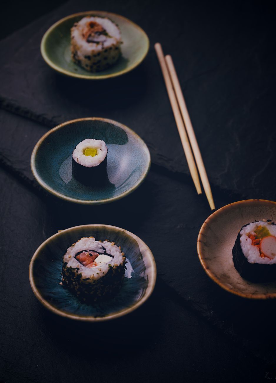 Cherry blossom-patterned ceramic plates and bowls arranged on a wooden table with spring flowers in soft natural light.