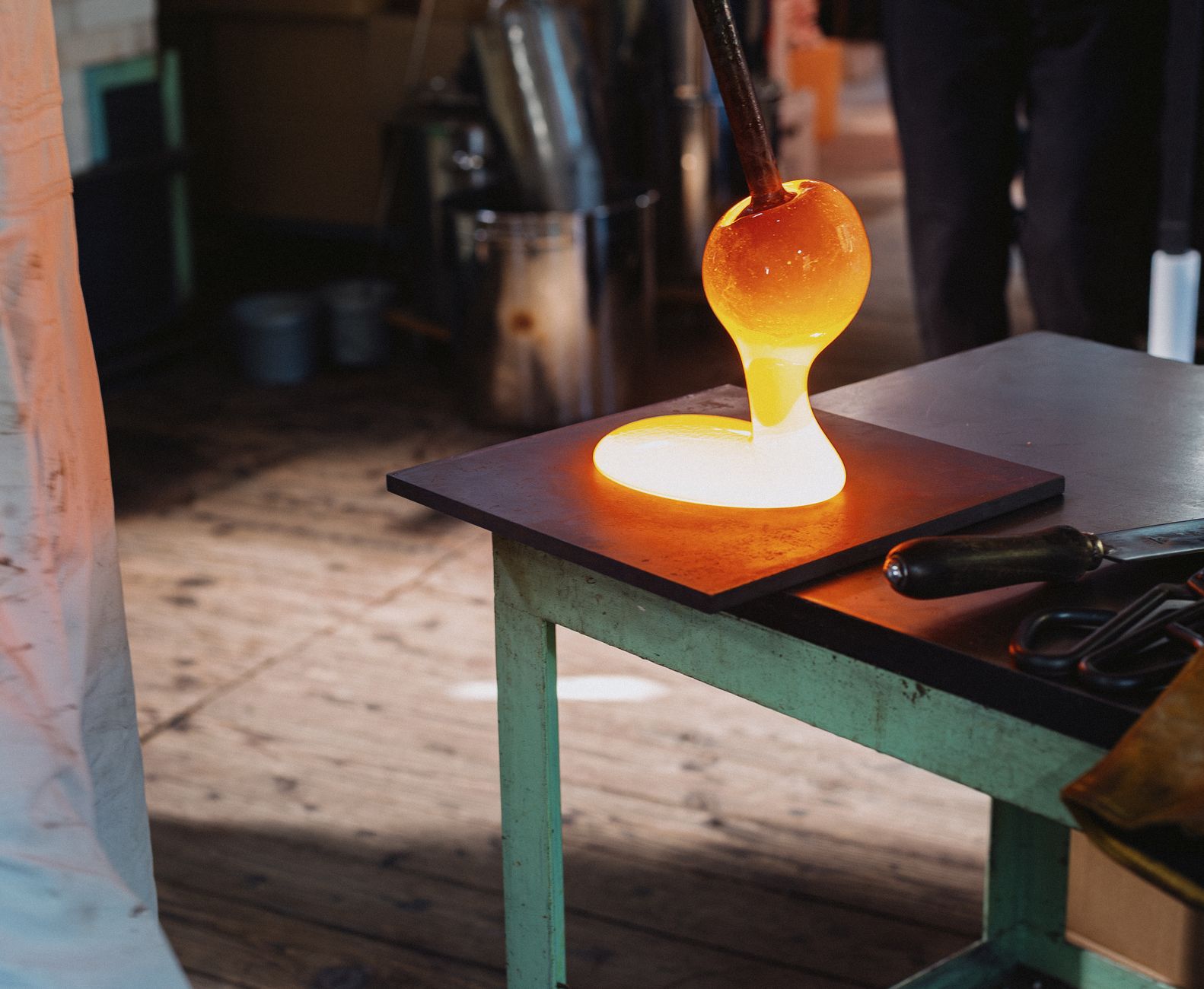 Artisan gathering molten Tsugaru Bidoro glass on a blowpipe from a furnace glowing with intense orange heat.