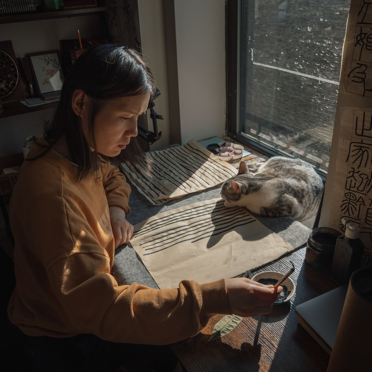 Hanging scroll with bold black calligraphy characters displayed in traditional tea room alcove beside bamboo flower arrangement.