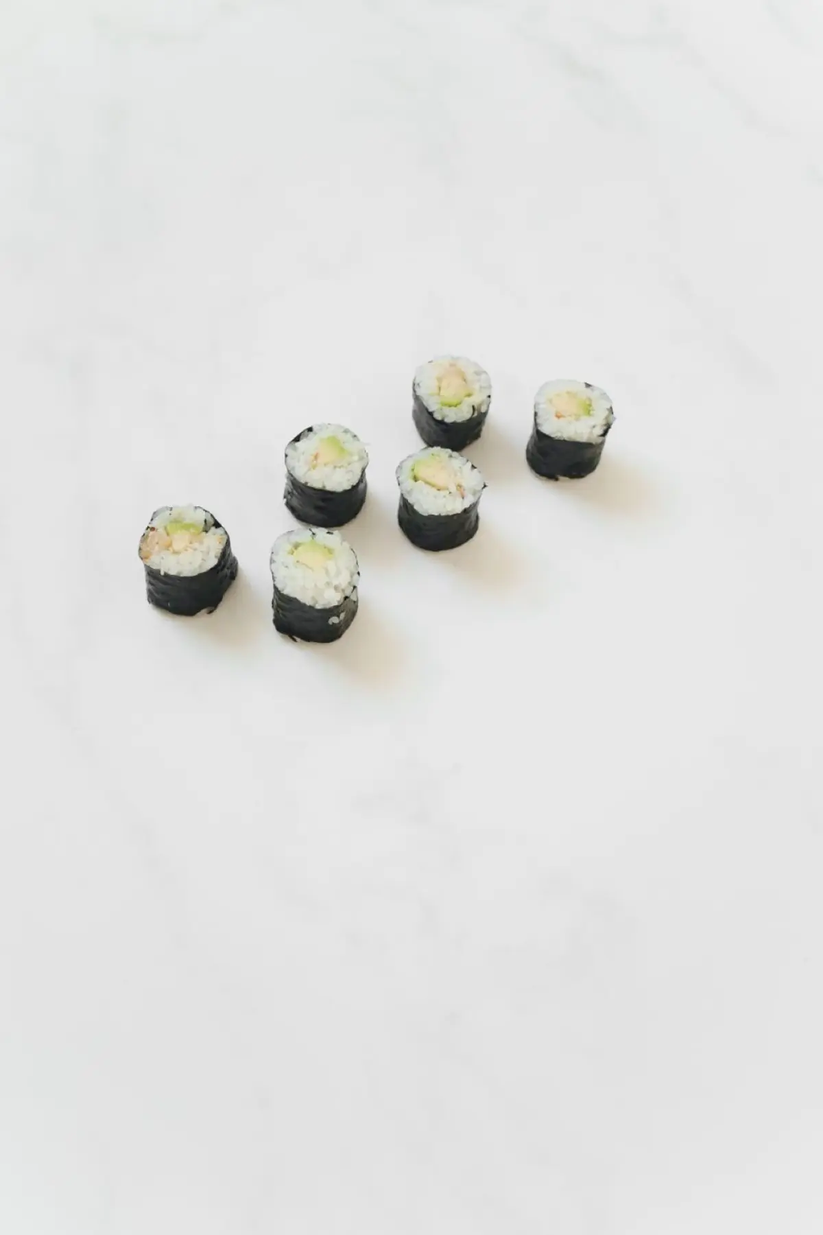 Glossy white sushi rice seasoned with rice vinegar, shaped into small oval mounds on a wooden cutting board.
