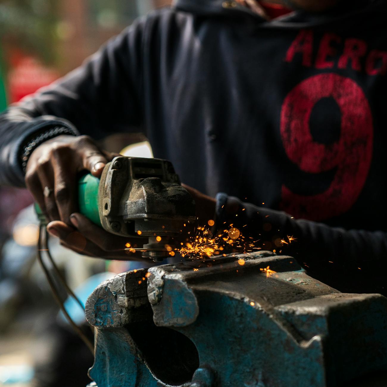 Swordsmith hammering glowing steel on an anvil in a traditional Japanese forge with sparks flying.