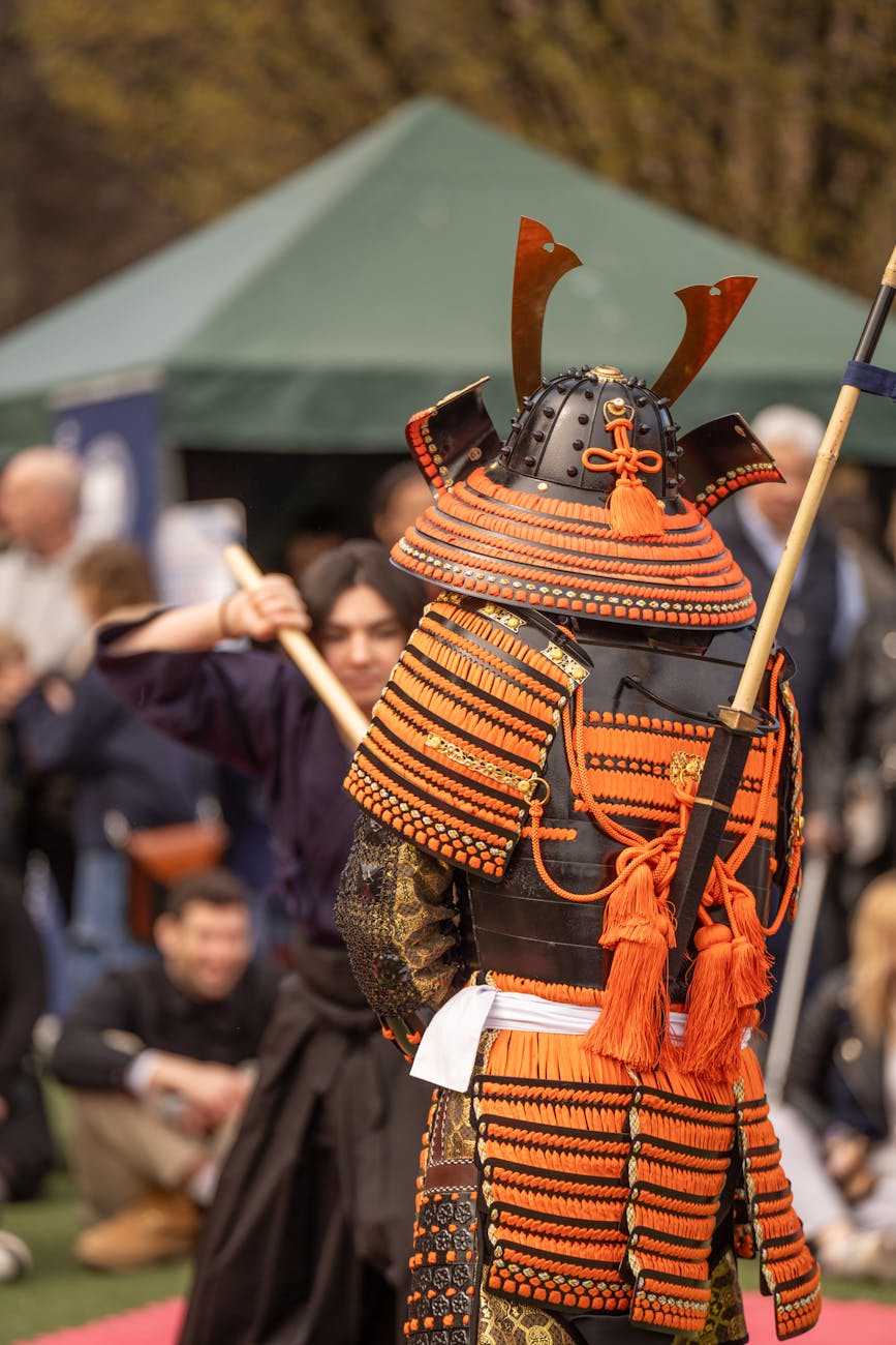 Complete traditional samurai armor displayed on a wooden stand, showing layered iron plates, ornate helmet with crescent crest, and protective shoulder guards.