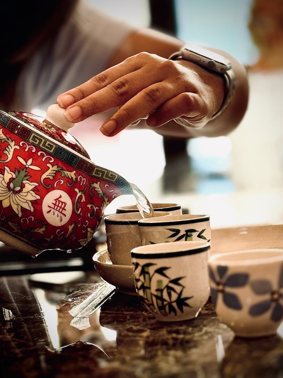 Hands cupping a warm yunomi tea bowl, fingers wrapped around smooth ceramic, steam rising from green tea inside.