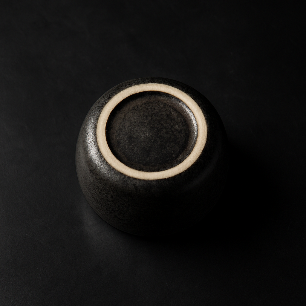 Hands carefully arranging a small collection of Japanese pottery bowls and cups on a wooden shelf at home.