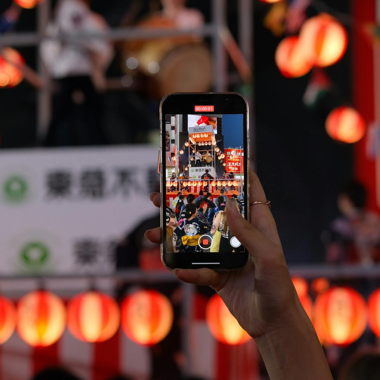 Colorful mikoshi portable shrine carried through crowded street during summer matsuri festival with paper lanterns overhead.