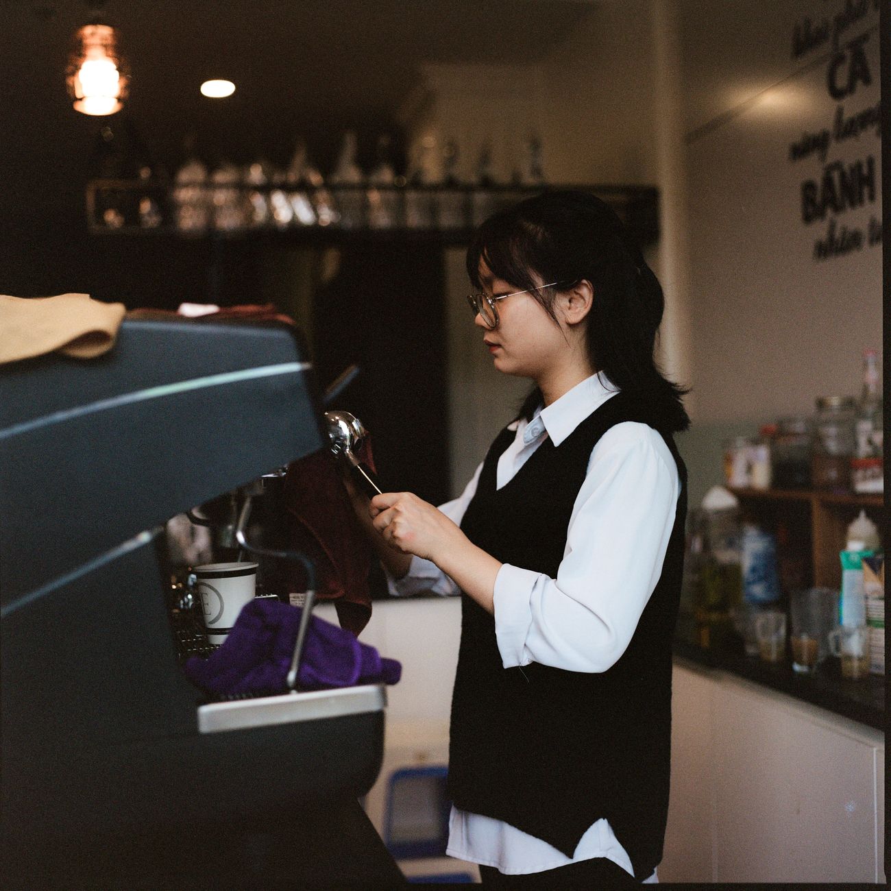 Japanese restaurant server bowing politely while presenting a wooden tray to a customer at a traditional counter seat.