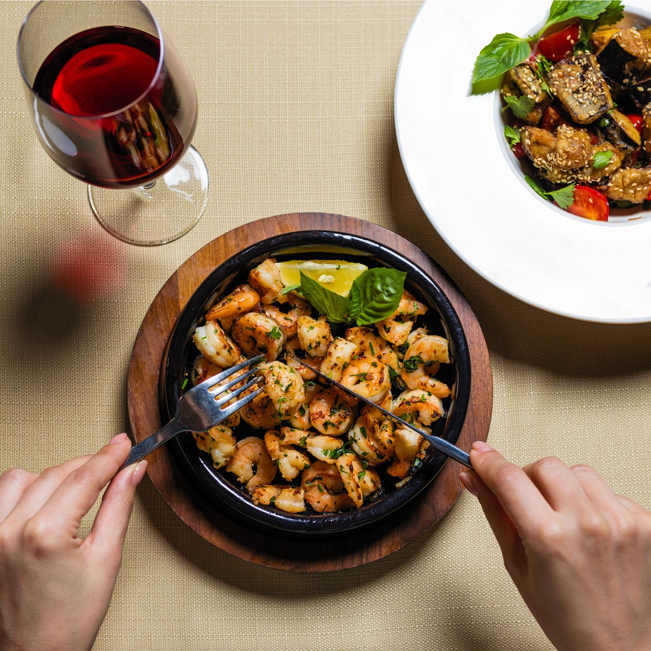 Person holding a traditional Japanese rice bowl in both hands while eating with chopsticks at a dining table.