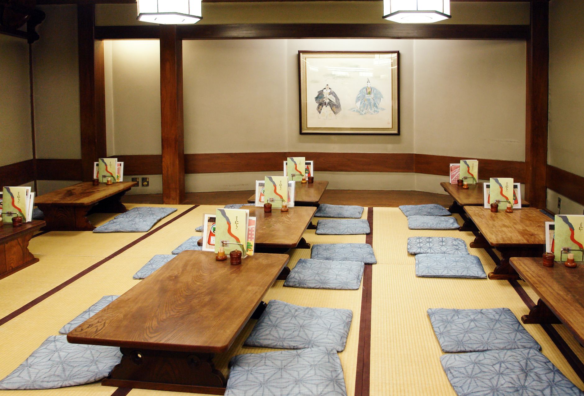 Traditional Japanese futon mattress and pillow neatly folded on tatami mat flooring in a minimalist room with shoji screens.