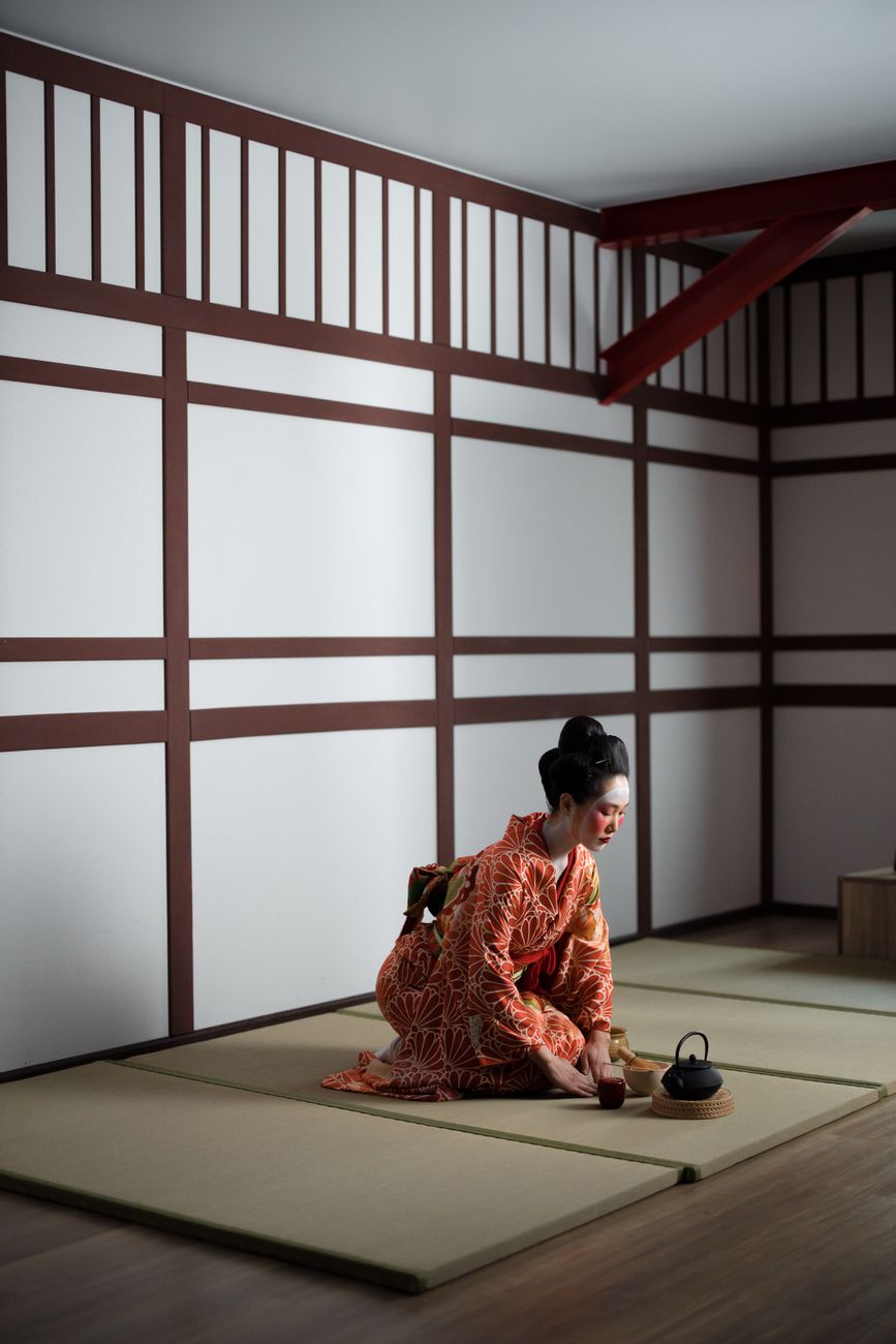 Traditional Japanese futon mattress and pillow neatly folded on tatami mat flooring in a minimalist room with shoji screens.