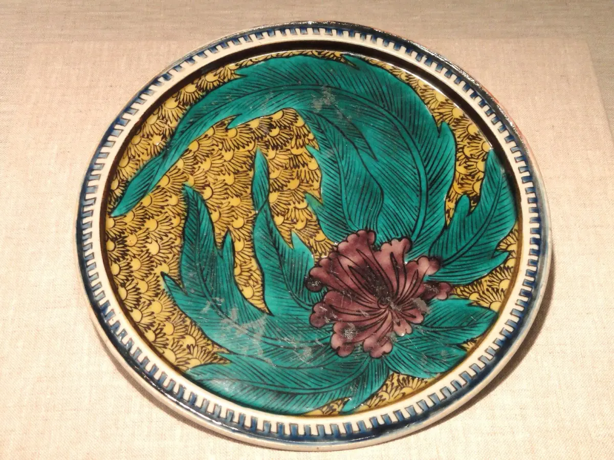 Vibrant Kutani porcelain plate featuring bold red, green, yellow, purple, and navy overglaze enamel in intricate floral patterns.