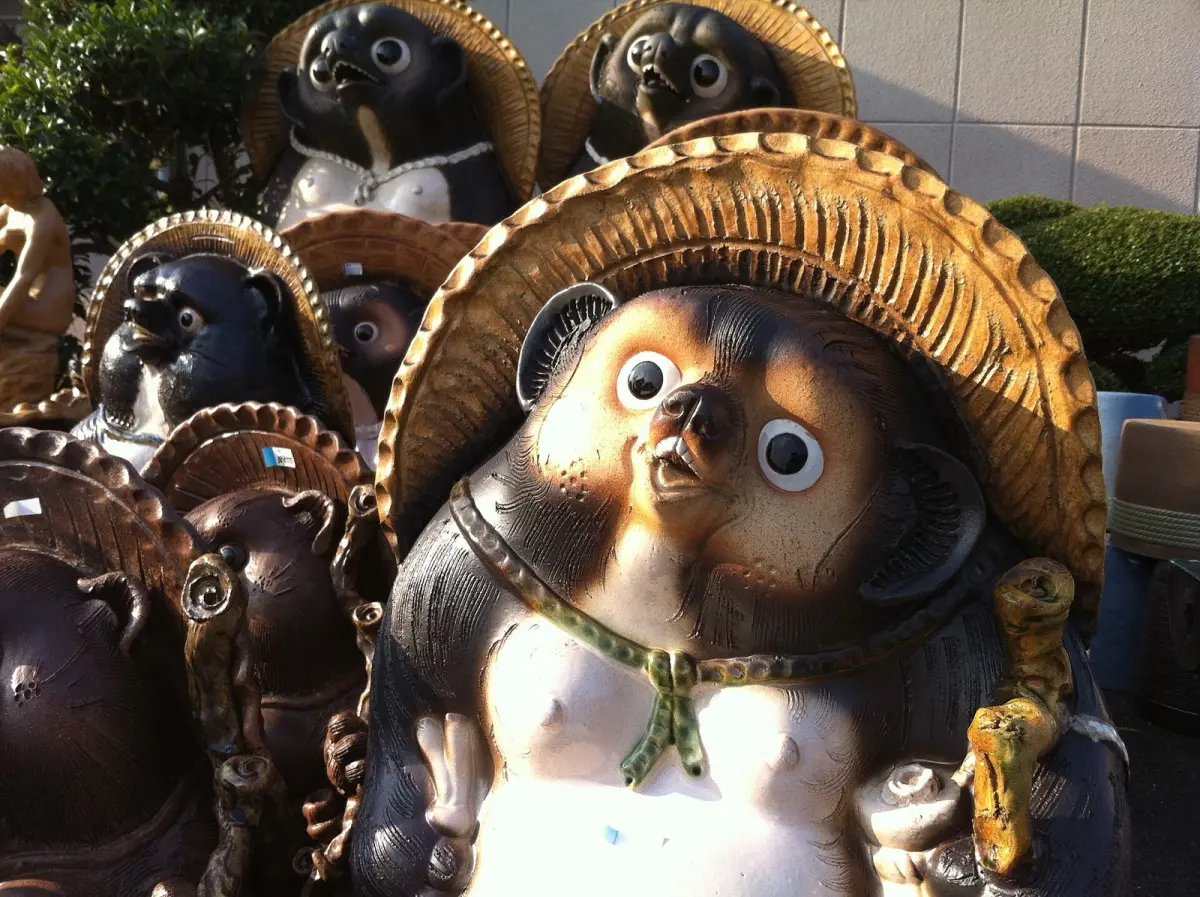 Traditional Shigaraki pottery tanuki statue with rough, earthy clay texture displayed outside a Japanese kiln workshop.