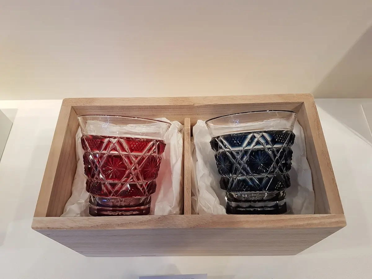Deep crimson and cobalt blue Satsuma Kiriko cut glass vessel displaying intricate geometric patterns against soft natural light.