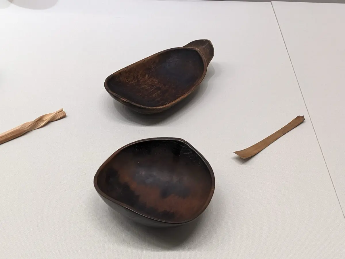 Artisan applying red urushi lacquer with a fine brush onto a wooden bowl in a traditional Wajima workshop.