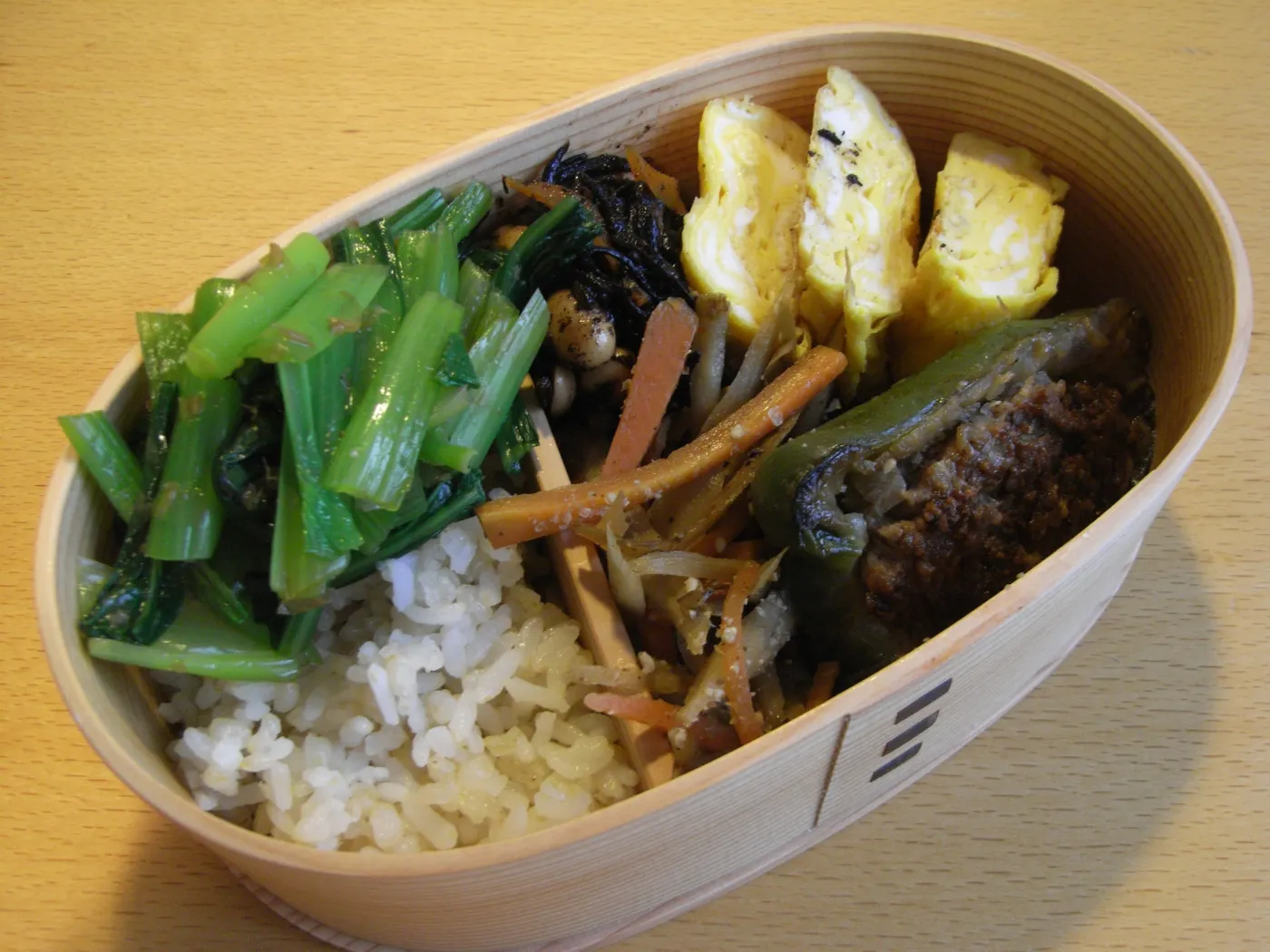 Cylindrical bentwood lunch box made from pale Akita cedar with visible wood grain and traditional cherry bark stitching.
