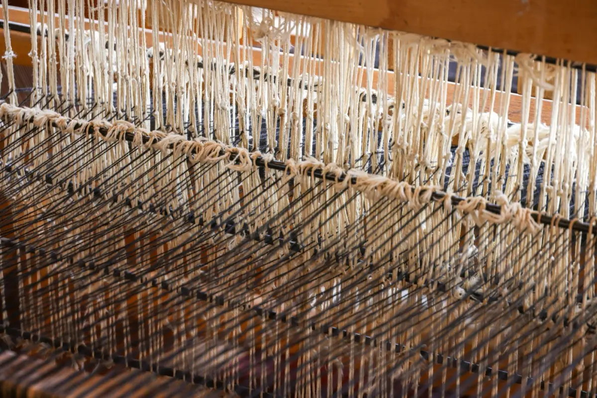 Traditional wooden looms with silk threads in a Kiryu textile workshop, showing the intricate weaving process of Japanese fabric artisans.