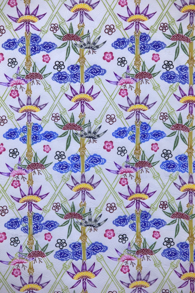 Vibrant bingata textile displaying tropical flowers and geometric patterns in coral, turquoise, and yellow dyes on white cotton fabric.