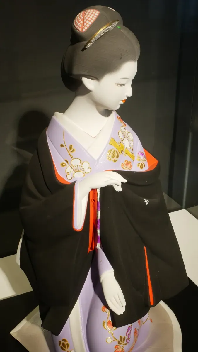 Traditional Hakata clay doll featuring a geisha in kimono with delicate hand-painted facial features and vibrant colors.