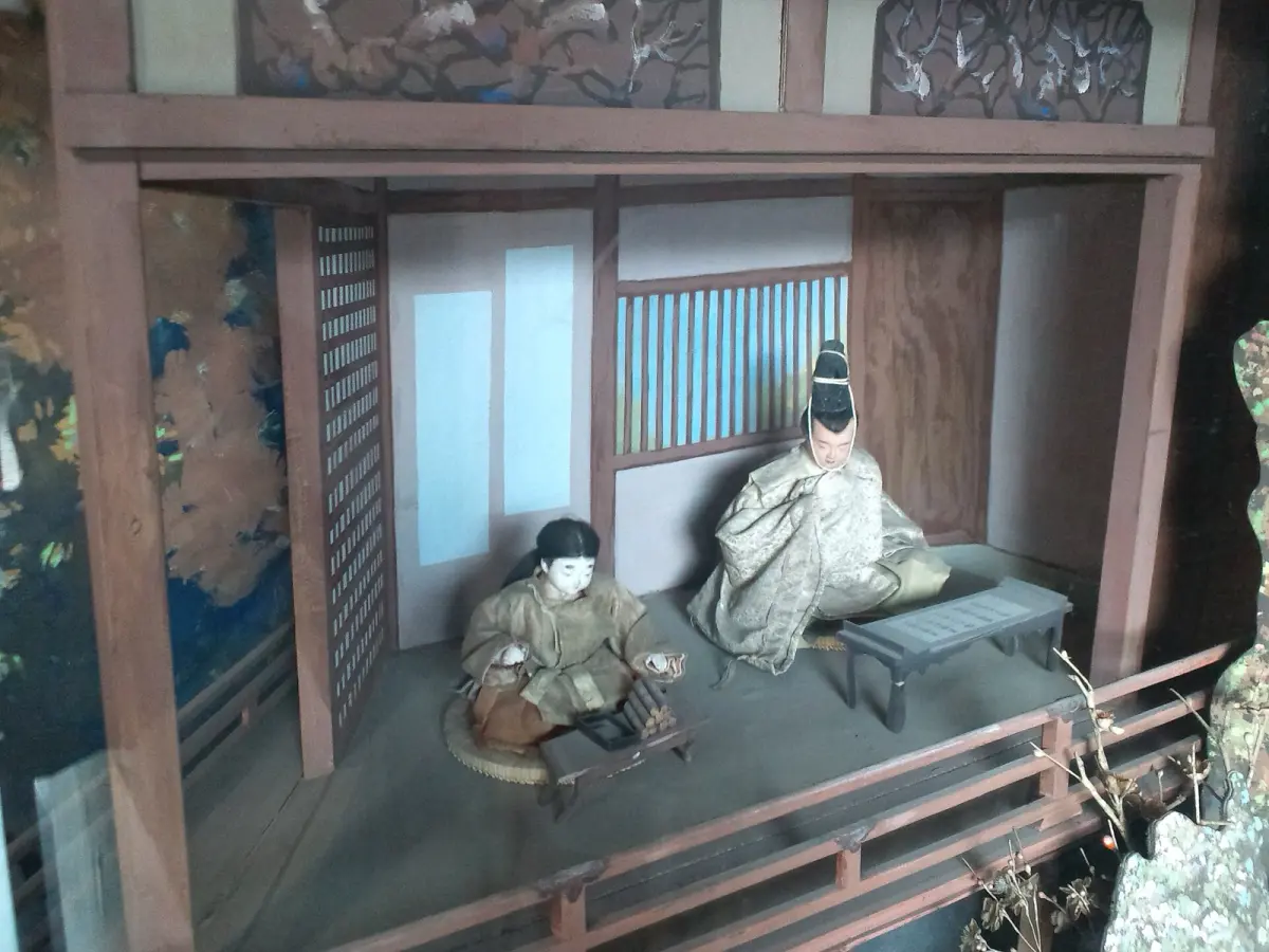 Traditional Hakata clay doll featuring a geisha in kimono with delicate hand-painted facial features and vibrant colors.