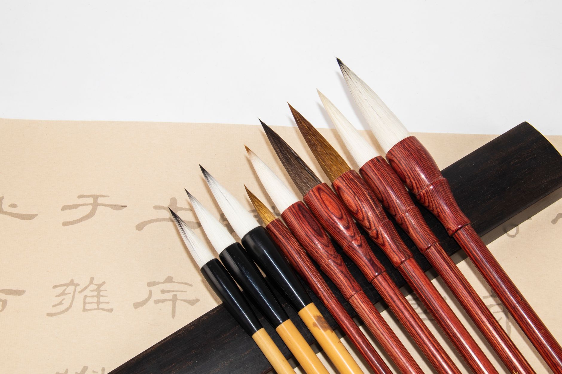 Artisan's hands carefully shaping a traditional Kumano makeup brush using natural animal hair in a sunlit Hiroshima workshop.