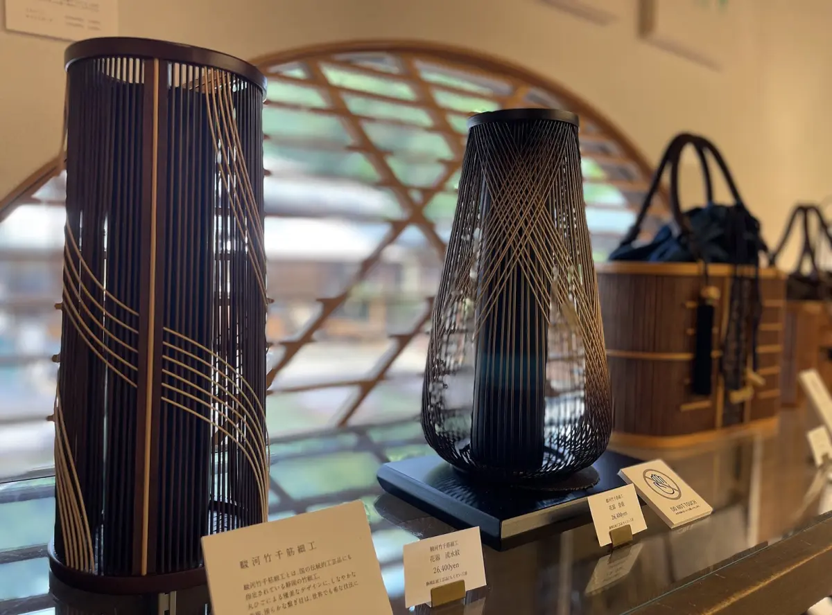 Artisan's hands shaping thin bamboo rods into intricate geometric patterns for traditional Suruga bambooware in Shizuoka workshop.