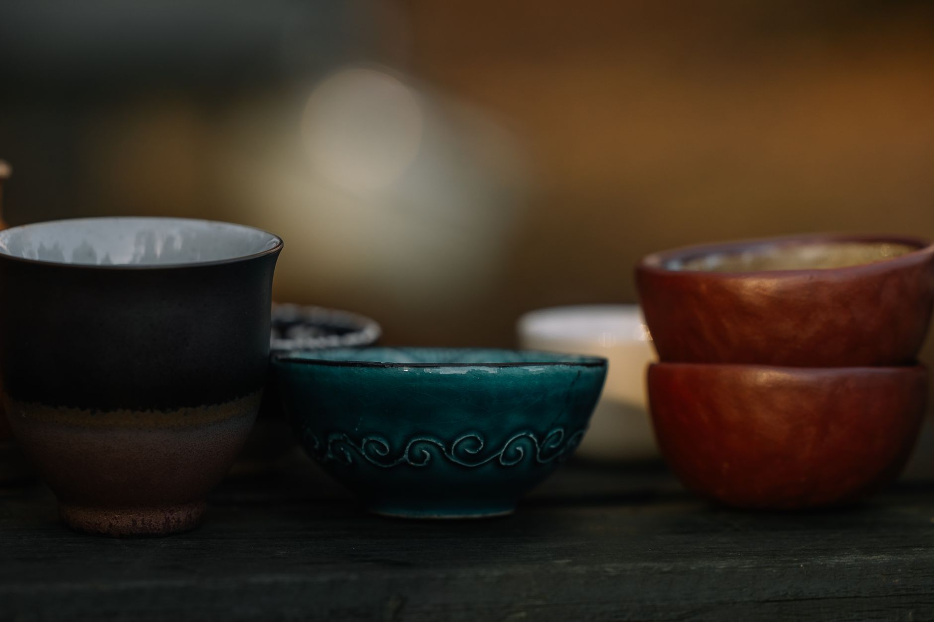 Close-up of traditional Japanese Oribe ware tea bowl featuring distinctive copper-green glaze with bold geometric black brushwork patterns.