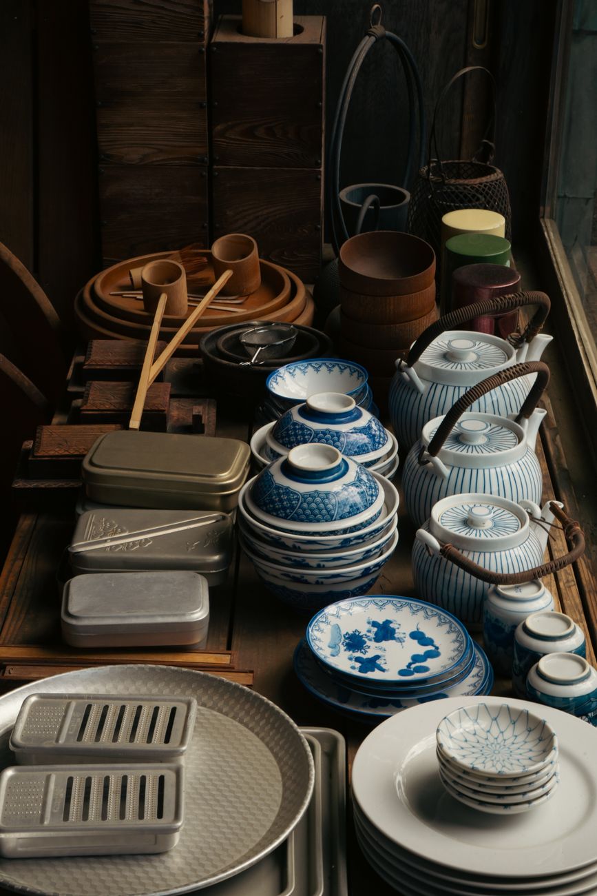 Artisan painting delicate floral motifs with cobalt pigment onto bisque-fired porcelain bowl using fine brush technique.