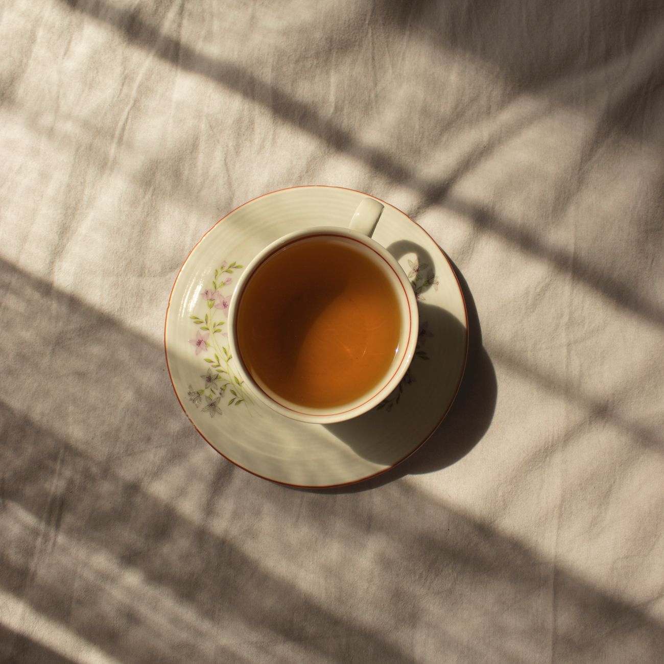 Vibrant green gyokuro tea leaves in a ceramic bowl beside a traditional Japanese teapot on bamboo mat.
