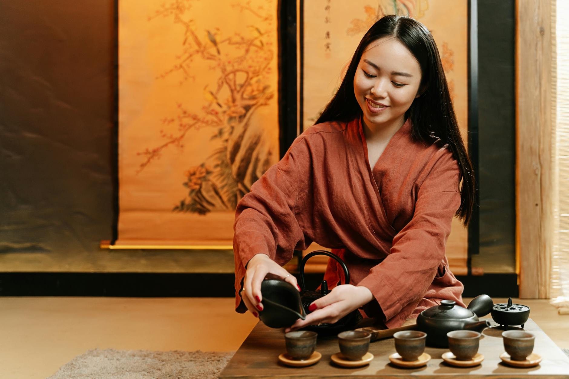 Hojicha tea leaves in warm brown tones next to a white porcelain teacup filled with amber roasted tea