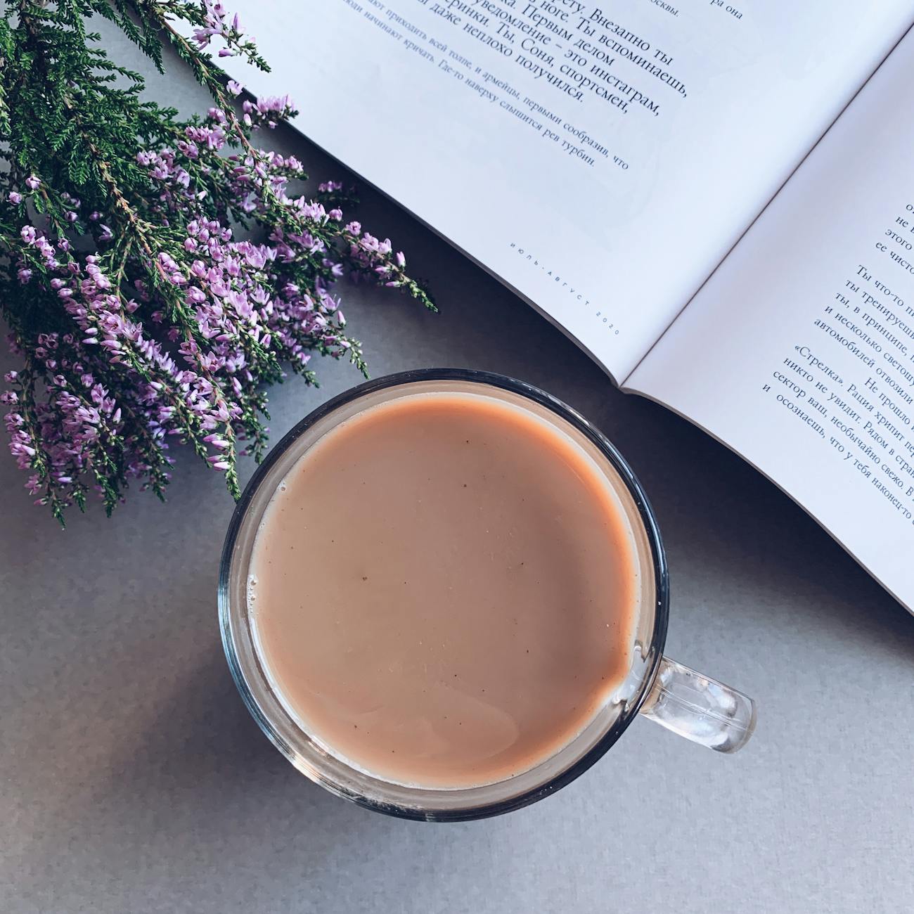 Hojicha tea leaves in warm brown tones next to a white porcelain teacup filled with amber roasted tea