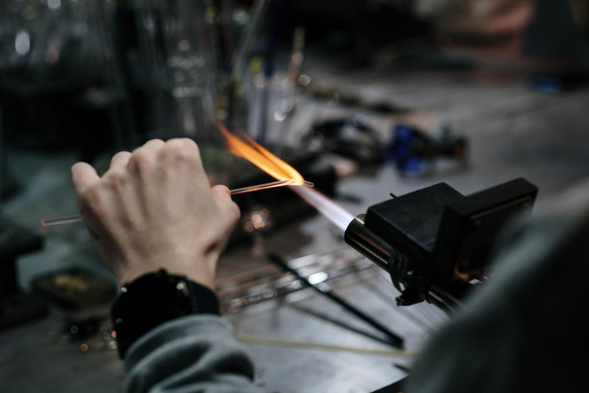 Artisan's hands guiding rotating crystal glass against a diamond-coated cutting wheel, creating precise geometric patterns in an Edo Kiriko workshop.