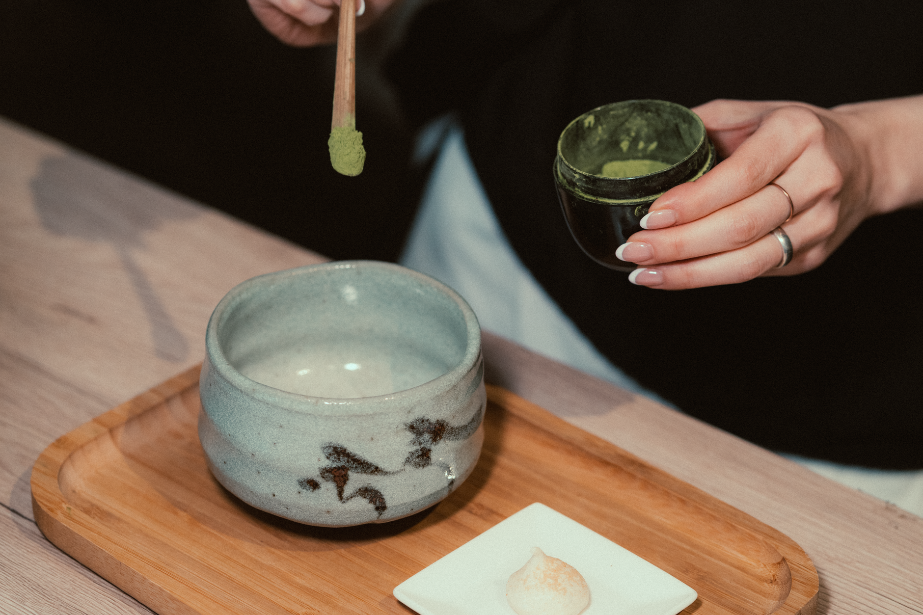 Two bowls of vibrant green matcha powder side by side showing different textures and color grades on bamboo mat.