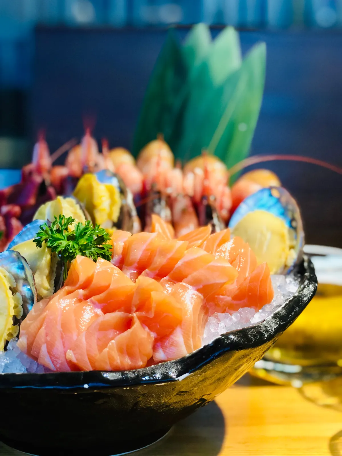 Thinly sliced tuna and salmon arranged in precise diagonal rows with shiso leaves and daikon garnish on white ceramic.