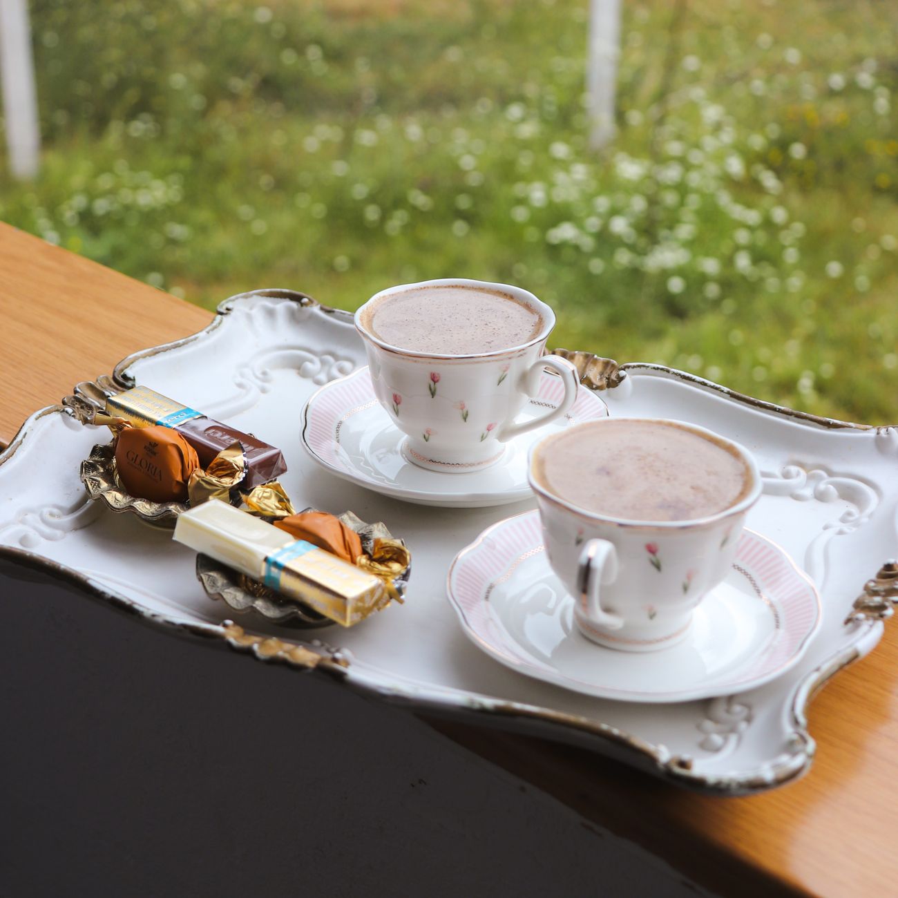Traditional Japanese matcha tea in a black ceramic bowl beside pink sakura wagashi on a lacquered tray