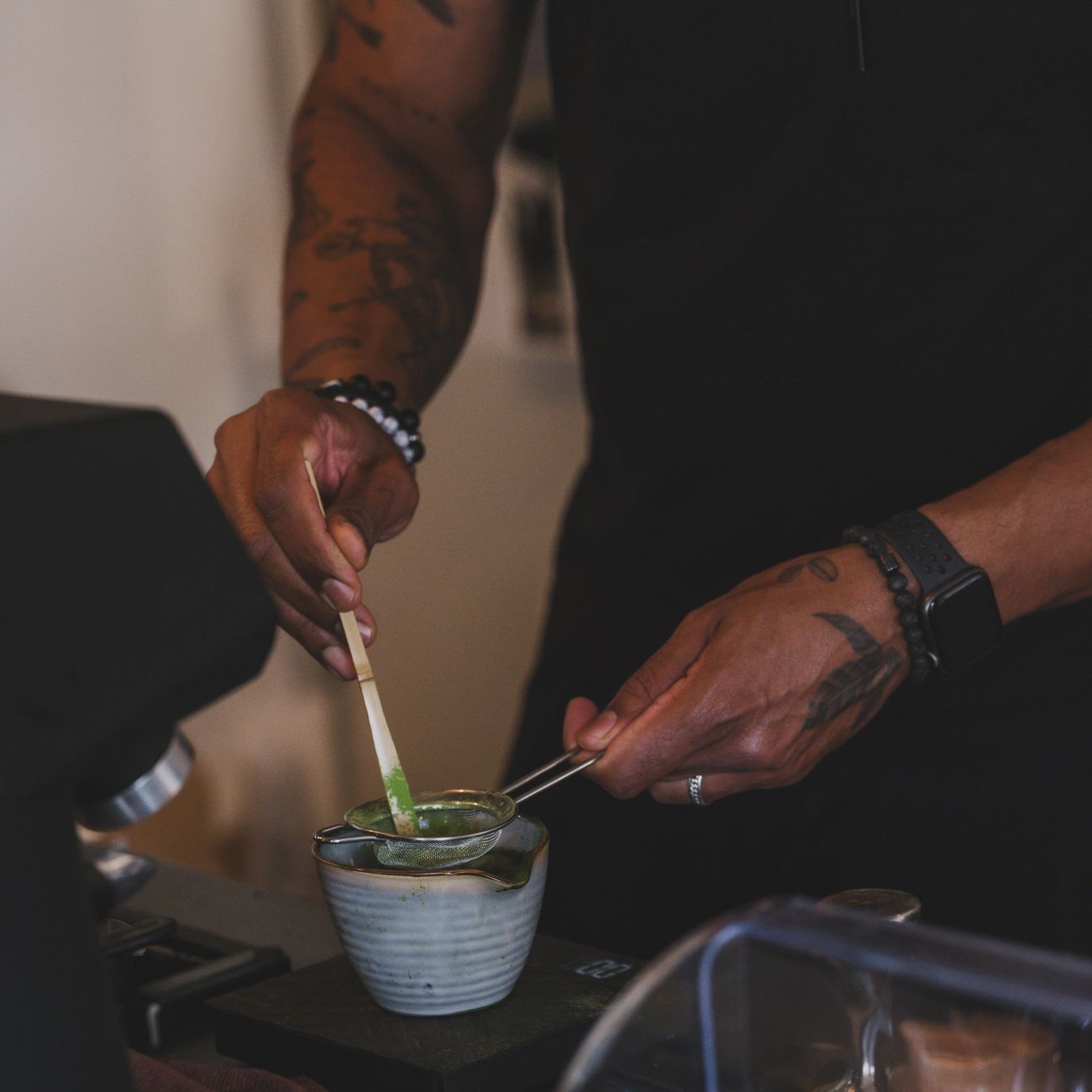 Guest's hands gently rotating a ceramic tea bowl clockwise to admire its decorative front before drinking matcha.