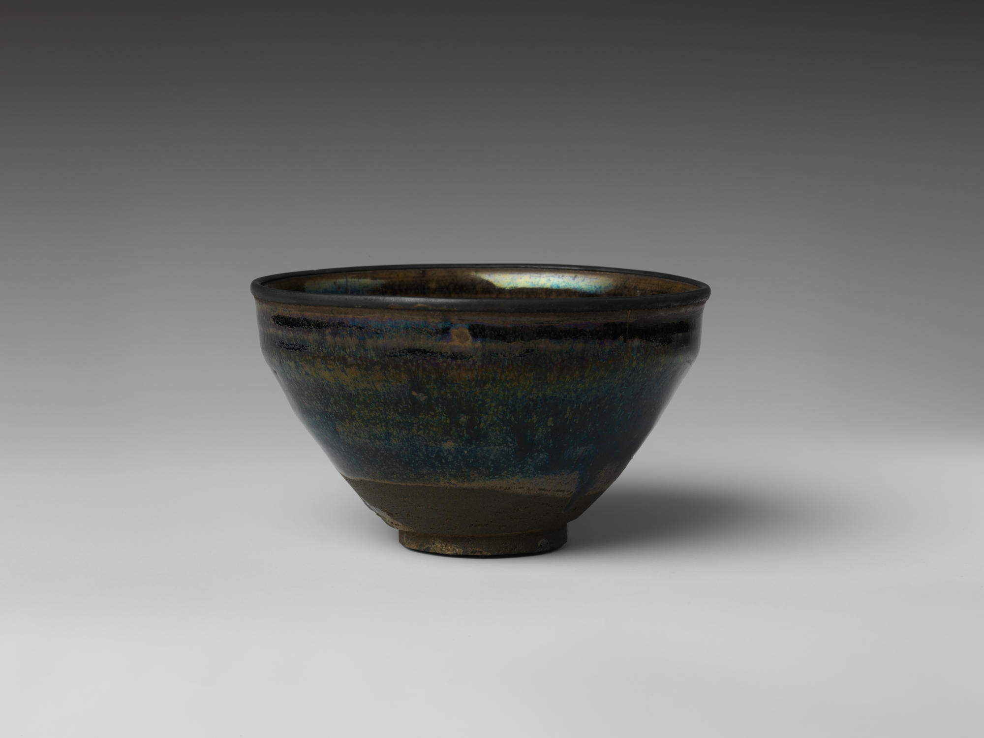 18th-century Japanese Seto ware tea bowl with dark iron-oxide glaze showing iridescent blue and gold sheen