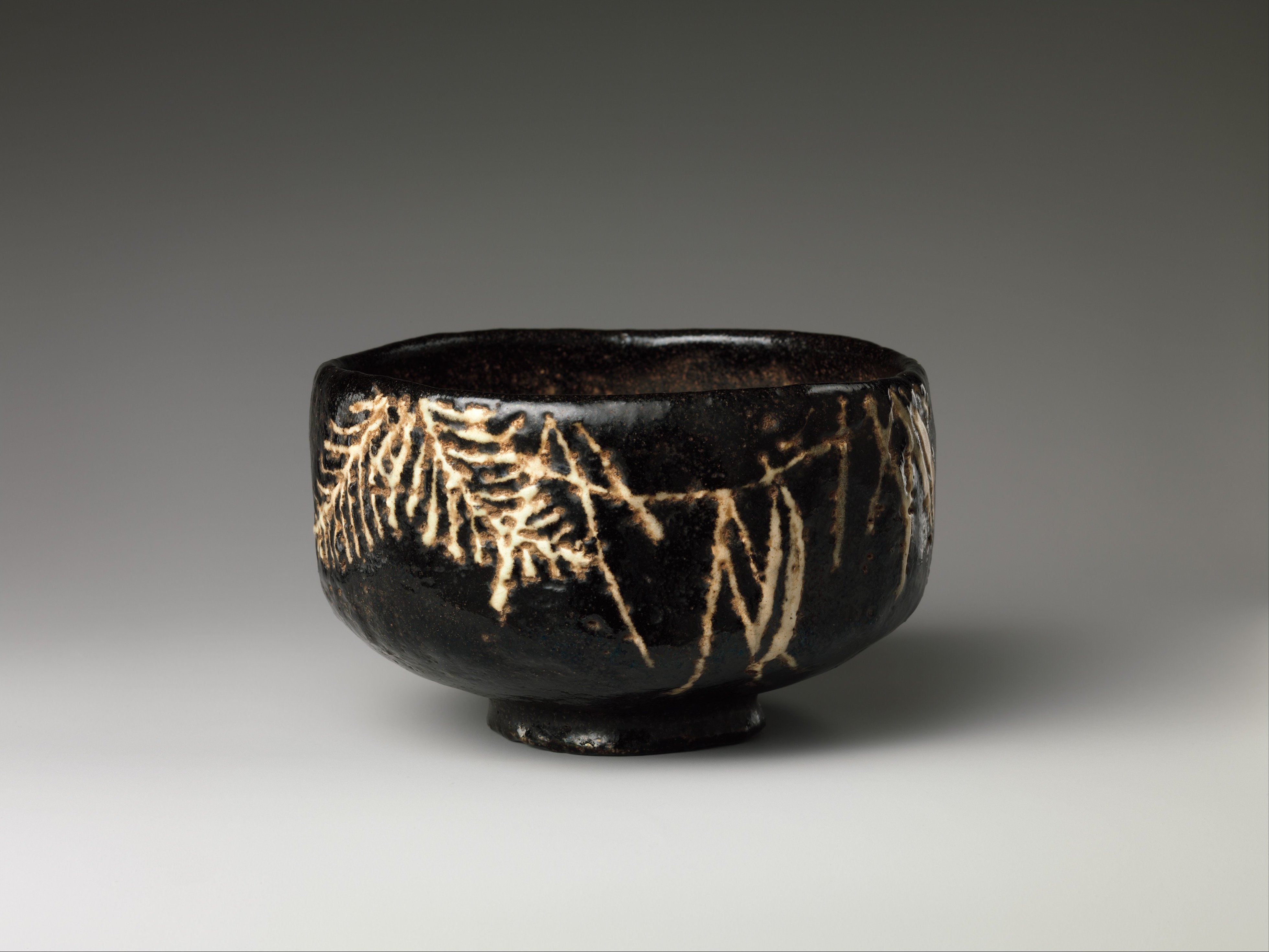 18th-century Japanese black-glazed tea bowl with a pale branch motif painted asymmetrically on one side