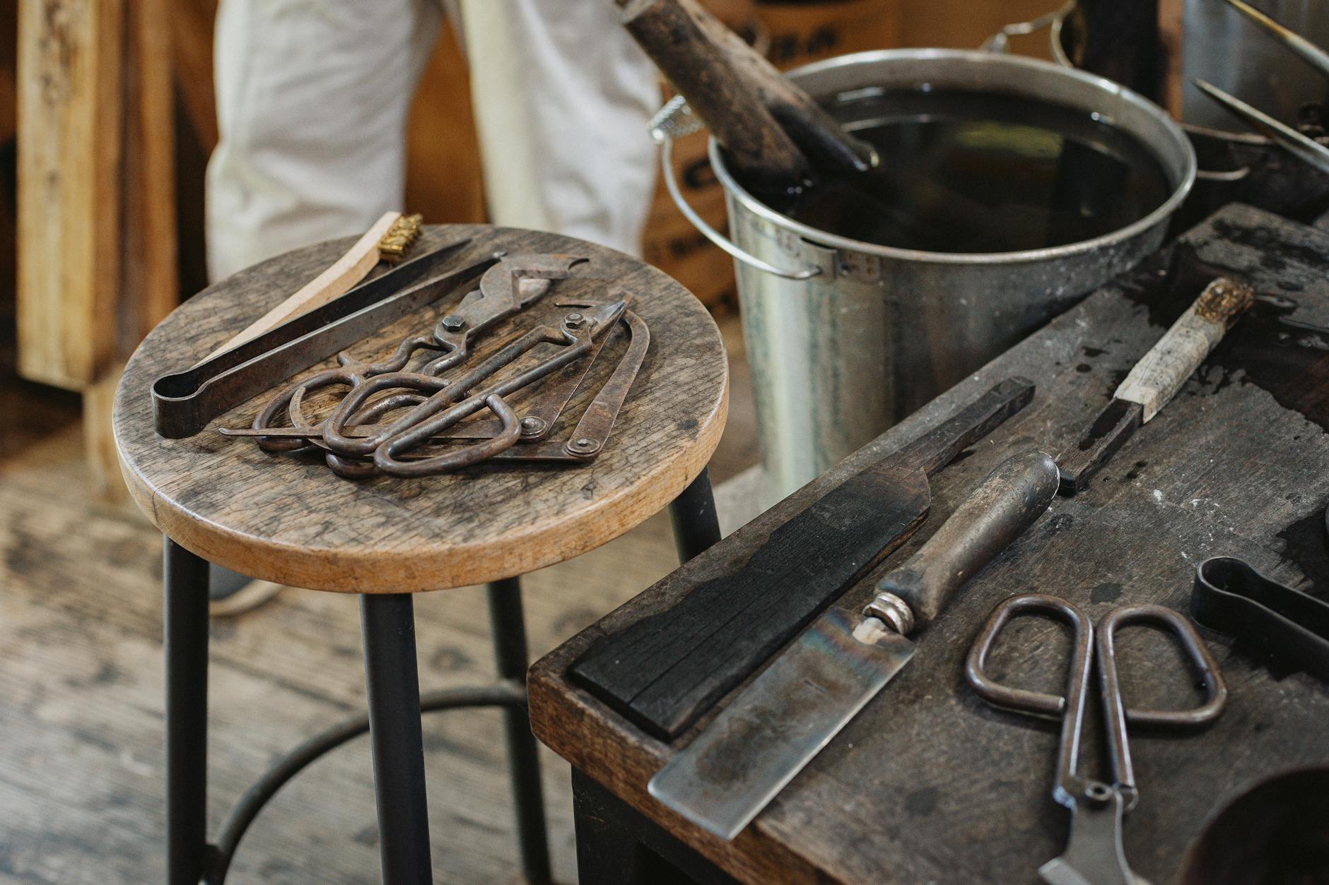 Artisan applying translucent urushi lacquer with a fine brush onto a wooden bowl in a traditional Japanese workshop.