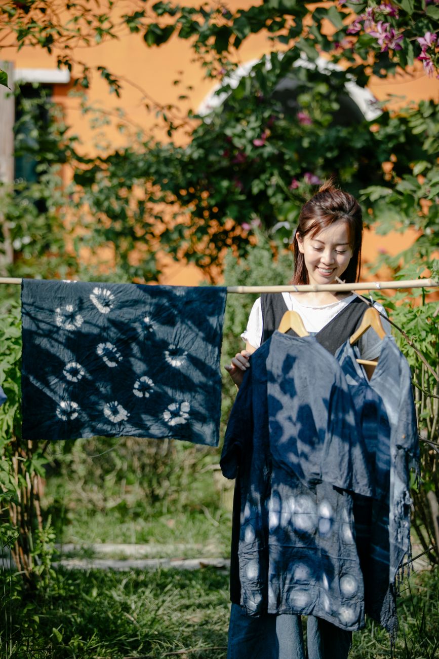 Artisan's hands submerging white cotton fabric into a deep blue indigo dye vat in a traditional Japanese workshop.